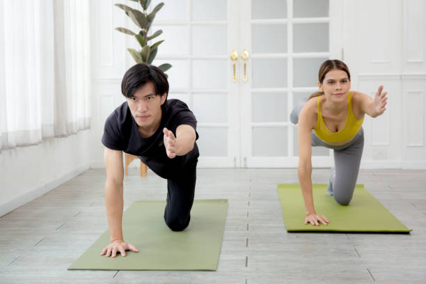istock Young woman and man practicing workout with posing plank while stretching hands and leg on mat at home, female and male doing weight training with strength and strong, two people, sport concept. 1442992471
