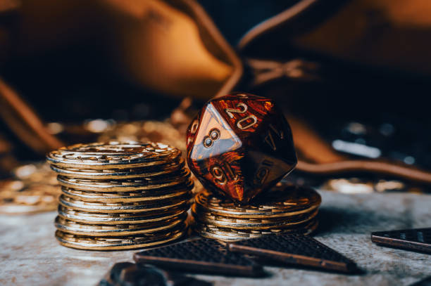 Close-up image of a red RPG die on top of golden gaming coins stock photo