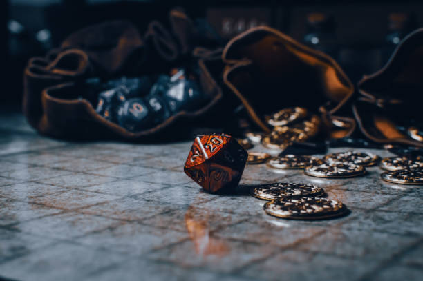 Red RPG die on a gaming grid with game coins and dice bags stock photo