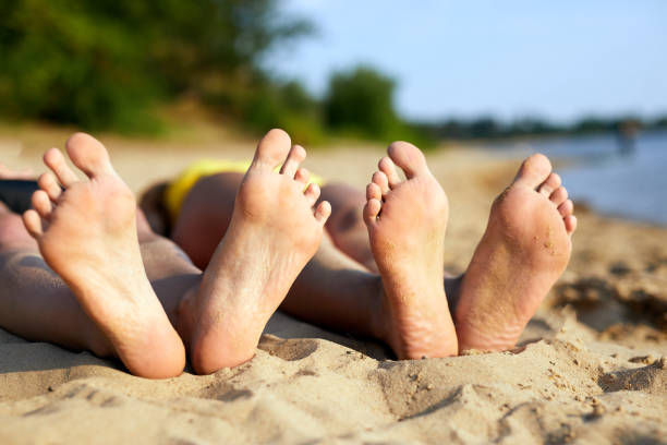 gambe di giovani donne sulla spiaggia. primo piano dei piedi della donna con la sabbia sulla spiaggia. vacanze estive. concetto di vacanza e viaggio. - sole of foot human foot women humor foto e immagini stock