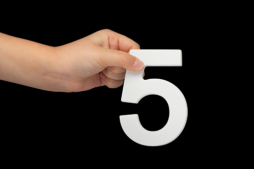 Number five in hand isolated on black background. Number five in the hand of a child holding on a black background. To be inserted into a project or design