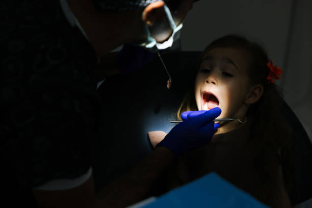 Shot of a young little girl lying down on a dentist chair while getting a checkup from the dentist
