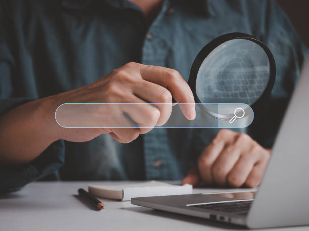 istock Man hold magnifying glass for searching information internet online 1443005657