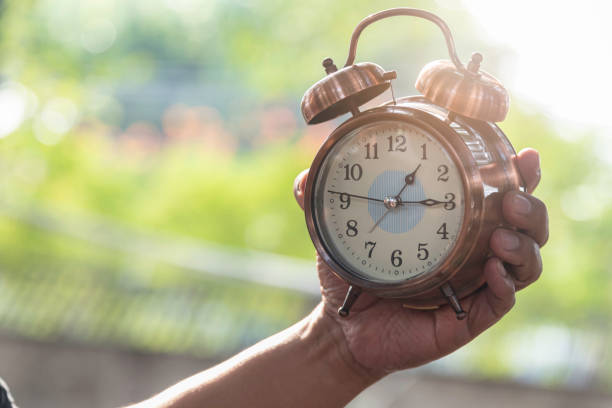 istock Hand hold alarm clock in park,check time appointment and time to work.nature background. 1443007300