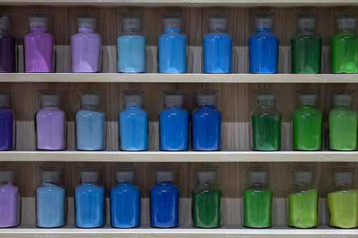 Colorful paint bottles on wooden shelves