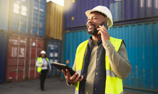 logistics, shipping and construction worker on the phone with tablet in shipyard. transportation engineer on smartphone in delivery, freight and international distribution business in container yard - business exports imagens e fotografias de stock