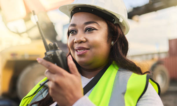 engenheira, mulher negra e walkie talkie para controle de gestão e comunicação com capacete no inspetor, gerente ou capataz no canteiro de obras. trabalhadora no estaleiro de logística na áfrica - inspector clipboard businesswoman white collar worker - fotografias e filmes do acervo