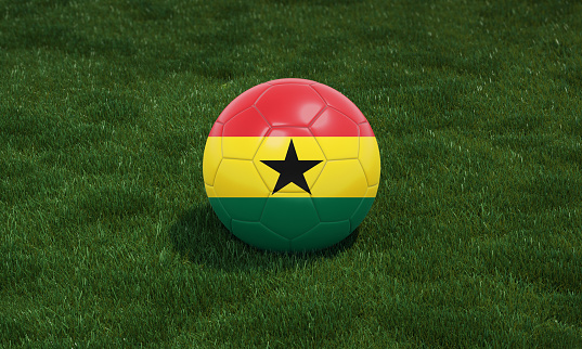 Soccer ball with Ghana flag colors at a stadium on green grasses background. 3D illustration.