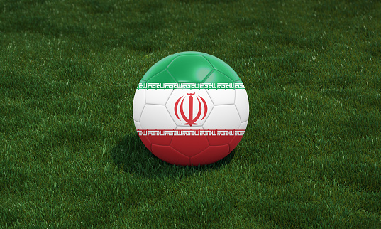 Soccer ball with Iran flag colors at a stadium on green grasses background. 3D illustration.