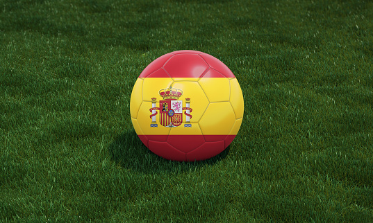 Soccer ball with Spain flag colors at a stadium on green grasses background. 3D illustration.