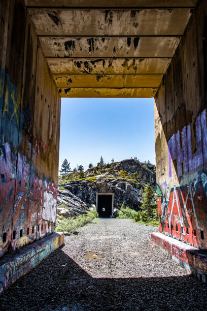 Hiking the tunnels - donner pass Looking through the  abandoned rail tunnels on Donner Summit. The original Central Pacific line, opened in 1887, was later covered with these "snowsheds"  as a way of keeping the tracks open during the harsh Sierra Nevada winters. This part of the line was abandoned in favor of a new route which opened in 1993. The abandoned tunnels have become an art installation for graffiti artists.
Donner Pass, California, USA
06/26/2022 robert michaud stock pictures, royalty-free photos & images