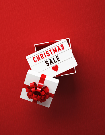 Christmas sale written lightbox sitting over white gift box on red background. Vertical composition with copy space, Great use for Christmas sale concepts.