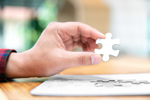 white jigsaw puzzle piece for complete connection concept in hand of business man for success solution and strategy