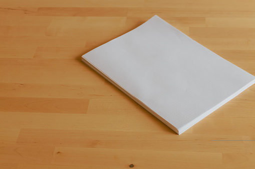 Office table with stack of paper sheets, top view. Blank sheets of paper on bright wooden office desk