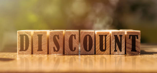 istock Word DISCOUNT made with building wooden blocks on table in sunlight. 1443027409