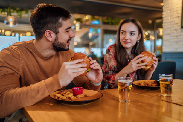 istock Couple eating burgers at restaurant 1443030744