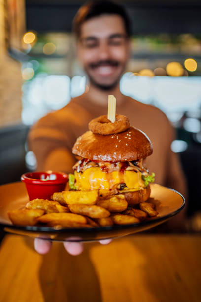 istock Young man holding a plate with a tasty burger 1443032025