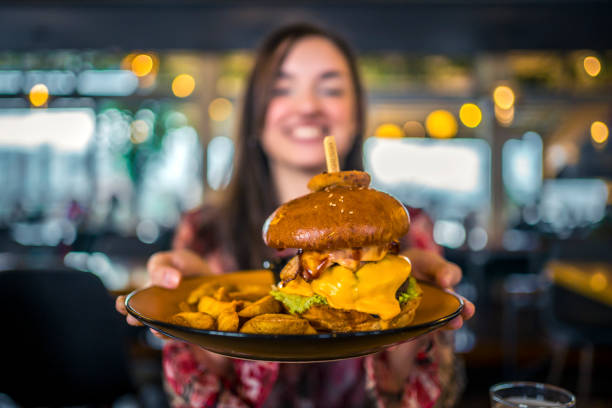 istock Young woman holding a plate with a tasty burger 1443032207
