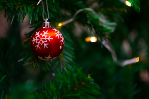 Close up shot of outdoor decorated Christmas tree with bright red balls on blurred fairy background. blurry steering lights Bokeh effect.