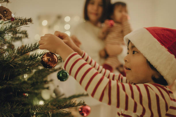 istock Little boy and young woman decorating christmas tree. 1443037217
