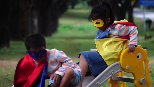 Children wearing masks and capes playing in the park.