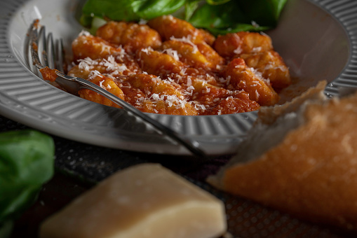 Gnocchi with marinara sauce garnished with fresh basil.