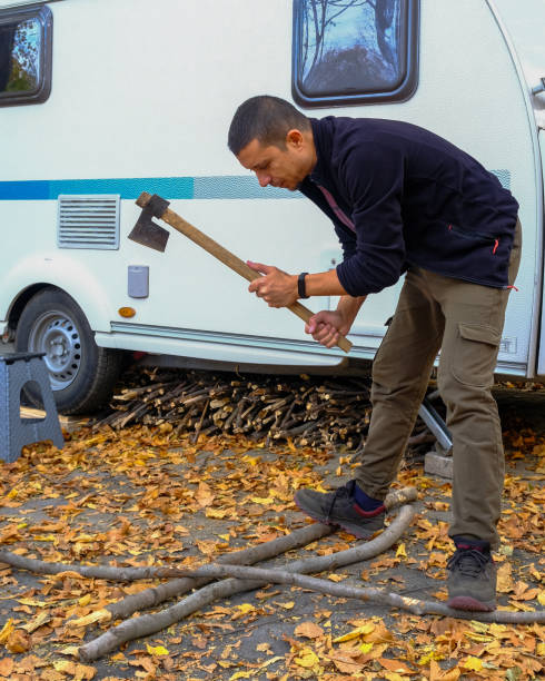 istock A man cutting wood with an axe by his camper trailer 1443038698