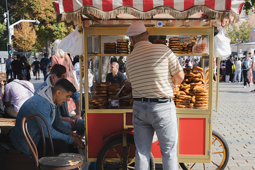 Istanbul, Turkey - October 1 2022: A traditional Turkish street vendor in the tourist district of Sultanahmet sells pretzels out of a food stand in Istanbul, Turkey.