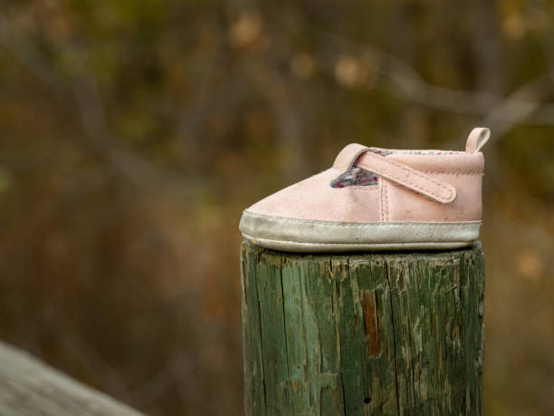 istock Pink baby shoe on a green fence post 1443045811