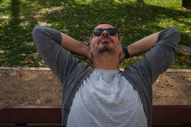 man relaxing sitting on a bench in a park