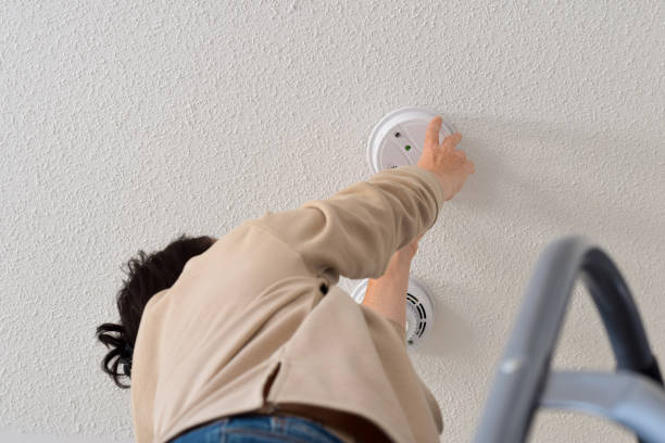 istock Woman reaching up for smoke alarm on ceiling at home 1443052113