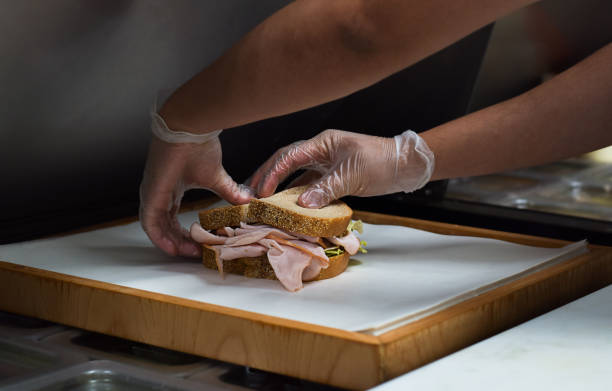 istock Restaurant kitchen employee wrapping freshly made sandwich for customer order 1443053680