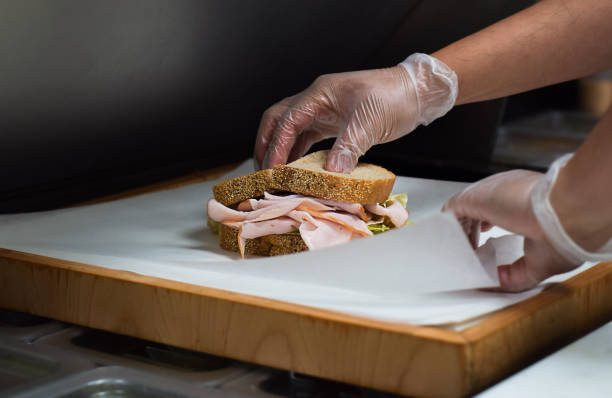 istock Restaurant kitchen employee wrapping freshly made sandwich for customer order 1443053688