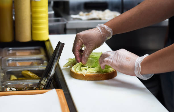 Kitchen employee preparing sandwich for customer food order