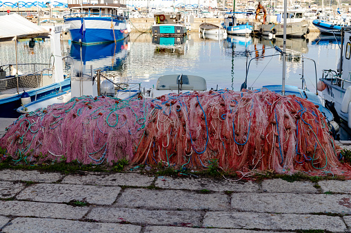 Colorful fishing net laying on a pier, closeup photo with selective focus and blurred port background