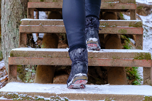 A woman climbs the stairs in winter. In winter, there is a risk of slipping on snowy stairs.