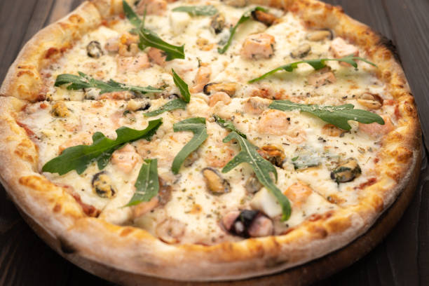 istock Seafood Italian Pizza with arugula on wooden table. 1443058967