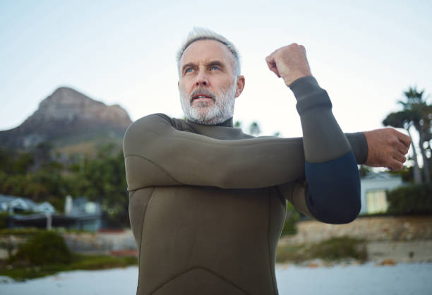 istock Fitness, surf and stretching with a sports man getting ready for a workout, exercise or training outdoor at the beach. Health, wellness and performance with a mature male at the start of his routine 1443059786
