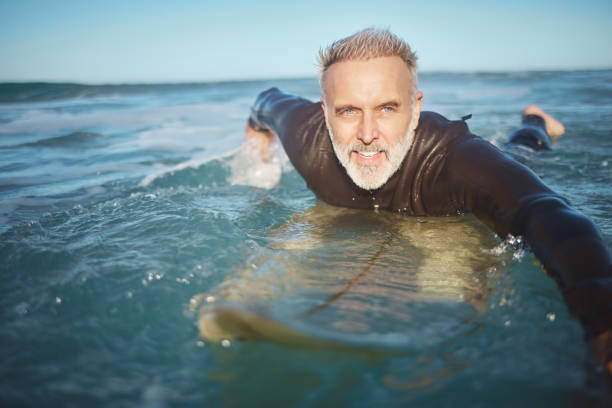 l’eau, la plage et l’homme surfant sur les vagues pour l’aventure pendant la retraite en vacances dans l’océan en été. surfeur mature à bord en mer en vacances sur une île lors d’un voyage à hawaii dans la nature - surfing men hawaii islands wave photos et images de collection