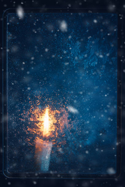 Christmas, new year, winter composition. Candle behind a frozen window with frosty patterns, copy space