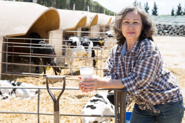 mungitrice matura in posa con bicchiere di latte - milker foto e immagini stock