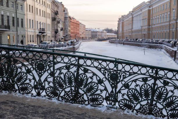 Winter Petersburg. Beautiful cast-iron grating of the Pevchesky Bridge fence against the backdrop of the frozen Moika River