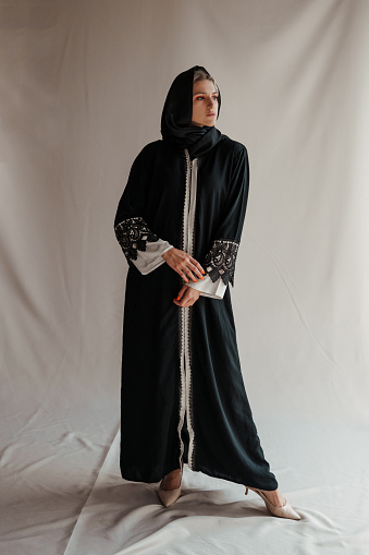 Beautiful muslim woman in traditional arabian abaya dress on gray background