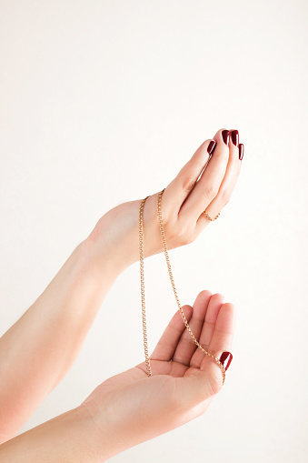 Women's hands with a bright manicure hold a gold chain