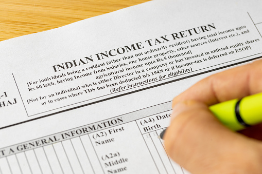 India income tax return, ITR1 form and hand with pen of person filling out tax return