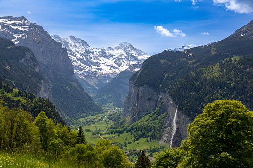 Landscape view of the Lauterbrunnen valley in Switzerland.  The Staubbach waterfall can be seen on the right and the Swiss Alps in the background.