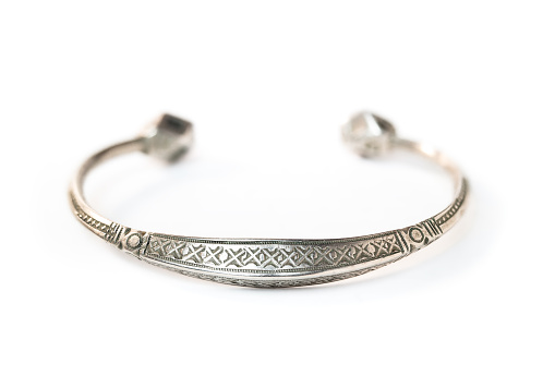 Perspective view of old small silver wrist torc with engraved pattern. Viking jewelry for female. Selective focus. White background.