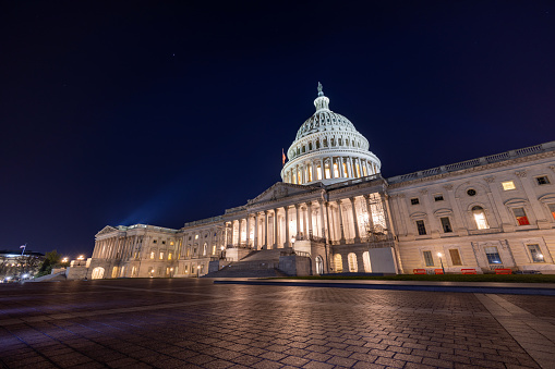 The east side of the United States Capitol Building in Washington, DC on a late autumn night. Spotlights illuminate the Capitol Dome and Statue of Freedom. No people are seen.