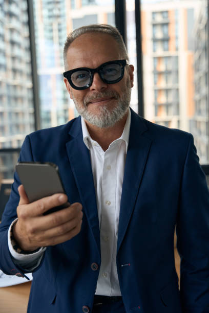 istock Pleased experienced entrepreneur posing with his smartphone at office 1443082267