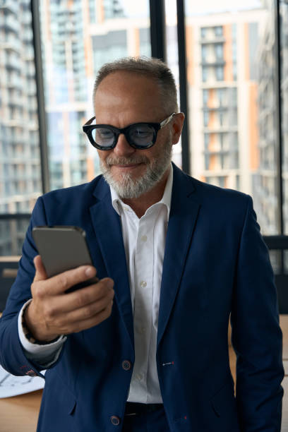 istock Contented middle-aged businessman checking his phone and smiling slightly 1443082298